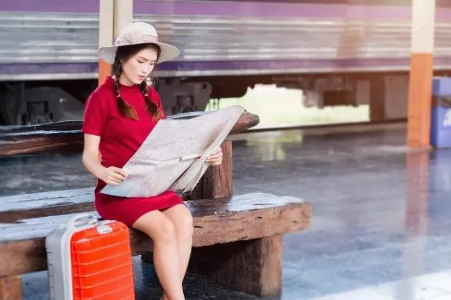 Pregnant mom on a holiday with her luggage and reading a map