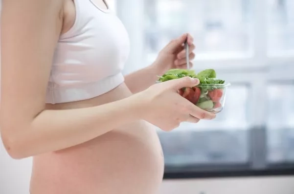 Pregnant mom holding a bowl of salad