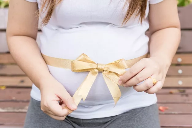 pregnant woman holding her belly in a park